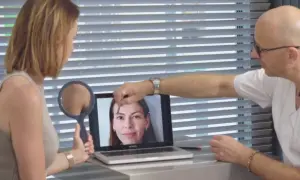 Lekarz pokazuje pacjentce na laptopie zdjęcie twarzy, analizując skórę.