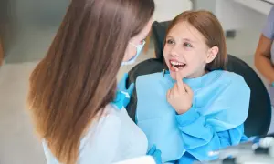 Uśmiechnięta dziewczynka podczas wizyty u stomatologa. Pedodoncja to specjalizacja, która dba o zdrowe zęby najmłodszych pacjentów.