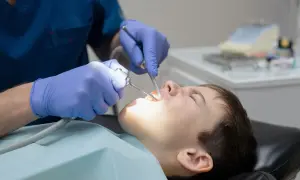 Chłopiec pod narkozą u dentysty. Sprawdź leczenie zębów pod narkozą cennik, by zapewnić komfort.