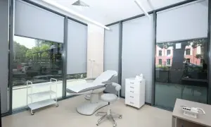 Gabinet dermatologii estetycznej z fotelem zabiegowym, szafką i wózkiem.