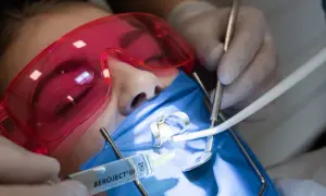 Precyzyjne leczenie kanałowe pod mikroskopem. Dentysta używa narzędzi i strzykawki do wykonania zabiegu.