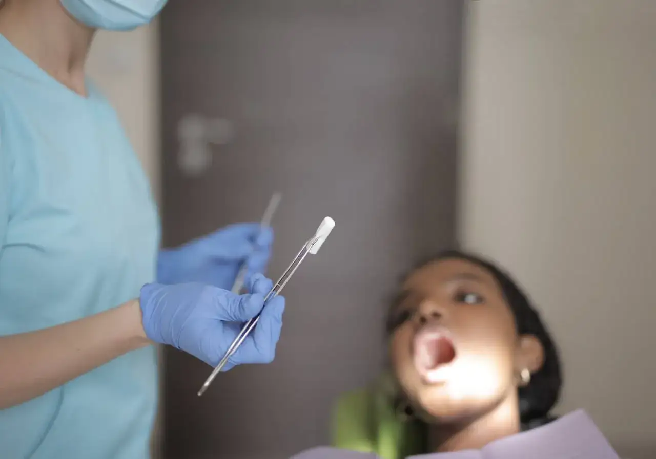 Dentysta z narzędziami przygotowuje się do badania zgryzu przewieszonego u dziecka.